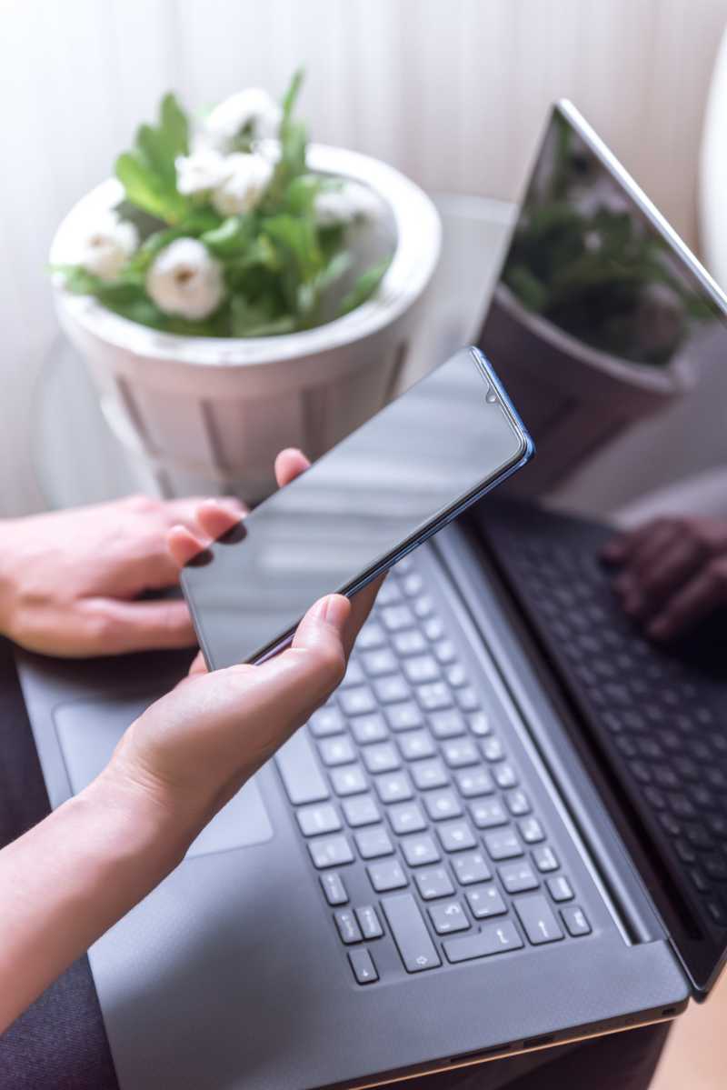 disparo-vertical-mano-femenina-sosteniendo-telefono-inteligente-computadora-portatil